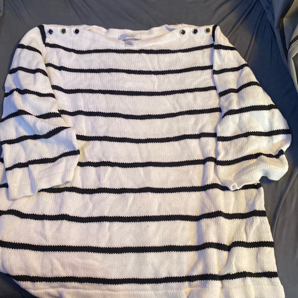 A white and black cj banks sweater with buttons around the collar bone